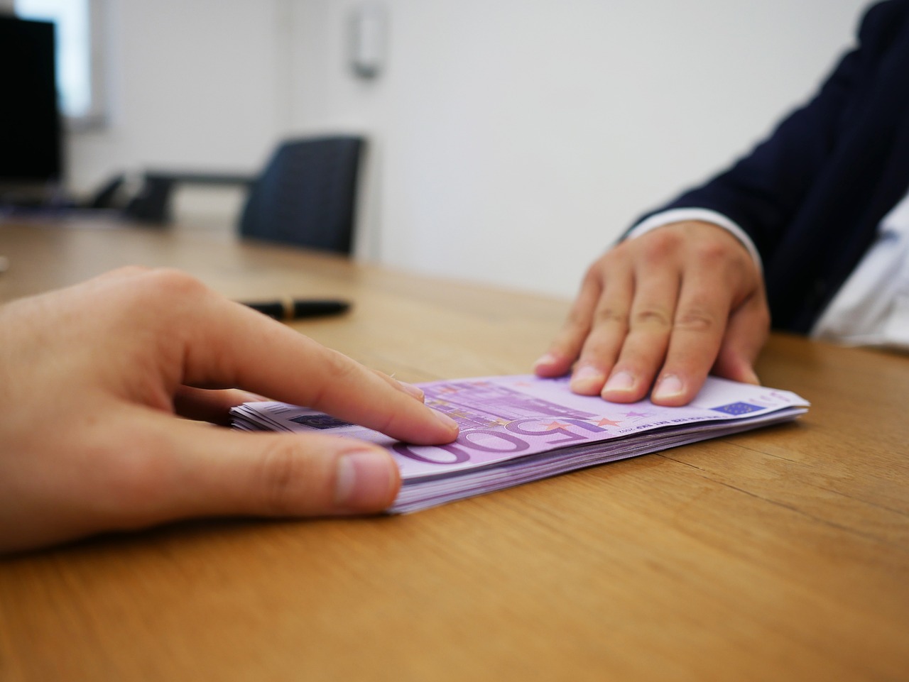 Sportello bancario con clienti che chiedono informazioni sul cambio banconote e diritti associati.