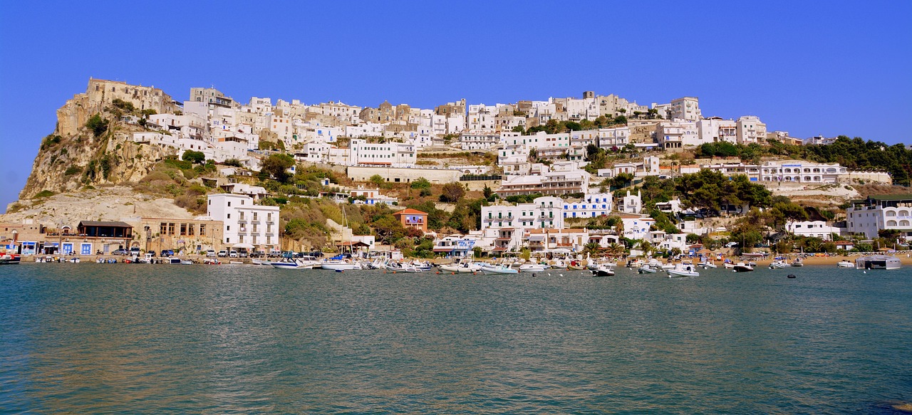Vista panoramica di Procida in primavera, con fiori colorati e il mare blu sullo sfondo.